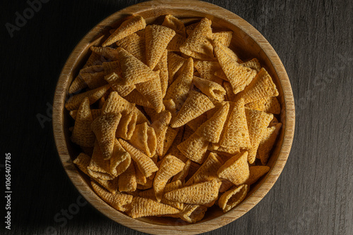  Un bol de madera lleno de conos de maíz crujientes, capturados en primer plano para resaltar su textura dorada y su irresistible apariencia. Un snack perfecto para disfrutar en cualquier momento.