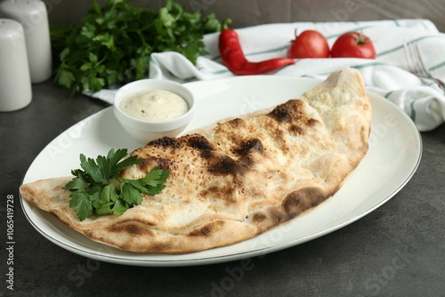 Delicious calzone served with sauce on grey table, closeup