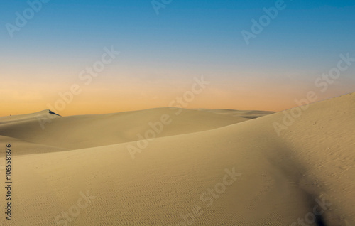 the sun sets between the desert dunes