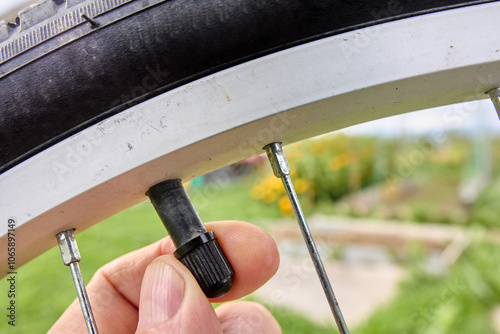 Cap of bicycle tire is removed by cyclist fingers before inflating tube with air.