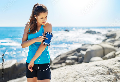 Running, arm band and woman by beach for fitness with race, challenge or marathon training. Earphones, health and female athlete runner by ocean for cardio workout with music for sports exercise.