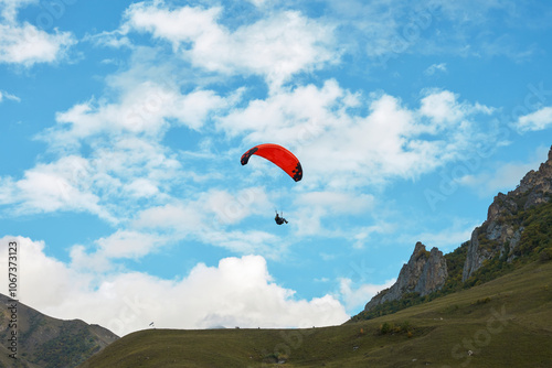 A lone paraglider in goraz against a cloudy sky towards the cliffs. Copy space.