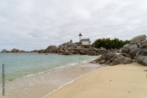 Le phare de Pontusval se dresse fièrement sur la côte bretonne, entouré de rochers aux formes arrondies et baigné par les eaux claires de la mer, sous un ciel typiquement breton.