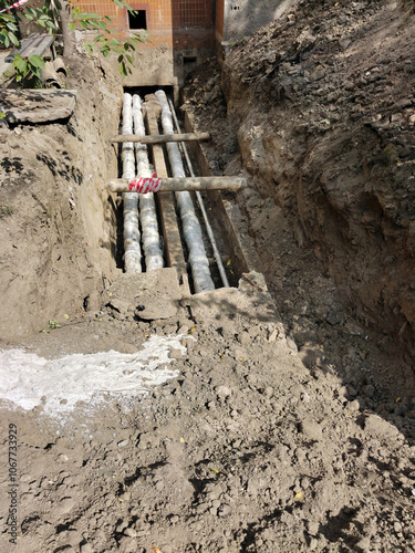 Repair of emergency sewer pipes near the house on the street in the city. The excavated pit is surrounded by a security fence