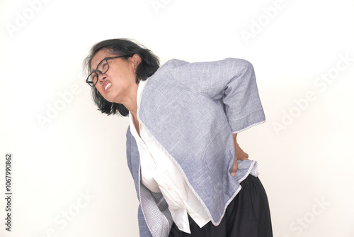 Asian middle-aged woman standing alone looking in pain, suffering from a backache