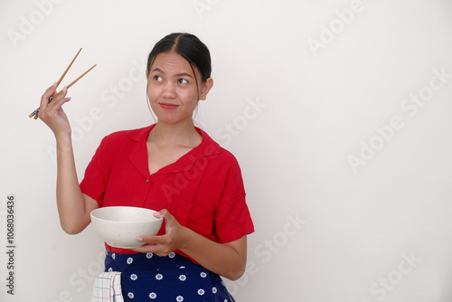 Indonesian woman standing alone, holding white bowl and chopsticks in her hands