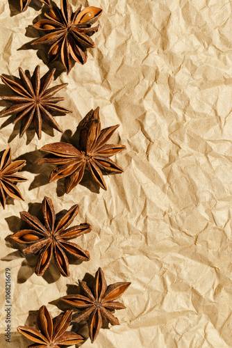 Anise stars background, top view close up macro photography fragrant spices dry anise seeds on crumpled baked paper, natural organic seasoning texture, food pattern, brown beige monochrome tone