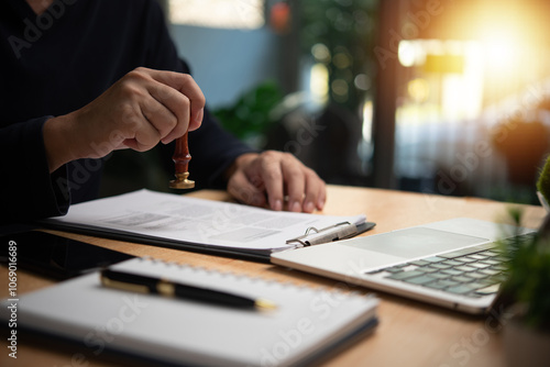 Man stamping approval on financial, banking, or investment documents at his desk official paperwork. rubber stamp with contract law and business documentation for legal agreements financial