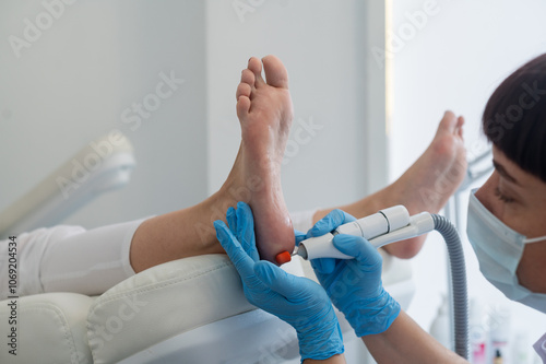 The podologist treats the feet using electric device machine. Patient on medical pedicure procedure, visiting podiatrist. Peeling feet. Foot treatment in SPA salon.Podiatry clinic