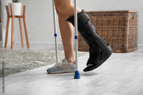 Young woman with broken leg and crutches walking at home, closeup