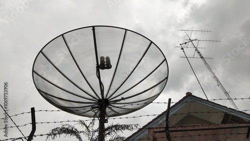 Television mesh parabolic antenna on dark cloudy weather