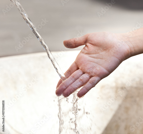 Hand catching running water from public fountain