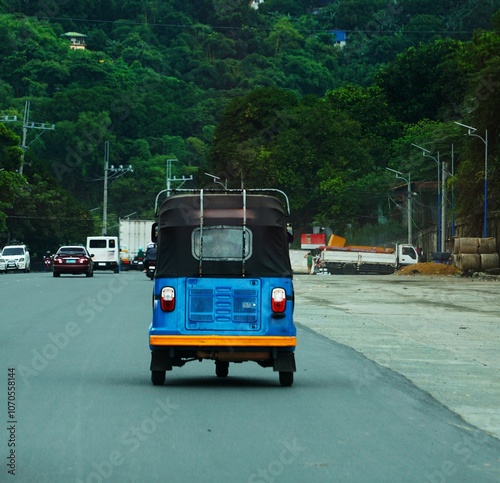 Tuk Tuk jedzie w stronę jungli. Niebieska autoriksza, szeroka droga i jungla. Tuk tuk car na Filipinach.