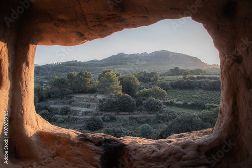 Paysage d'une colline pendant un lever de soleil vue d'une grotte aux roches oranges. 