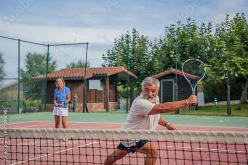 Senior tennis player hitting backhand shot with partner on court