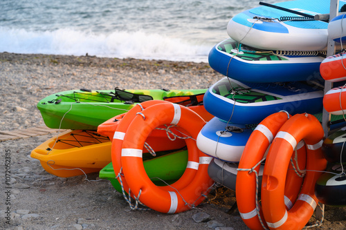 Kayaks and life preservers sit on the beach, ready for a day of water fun