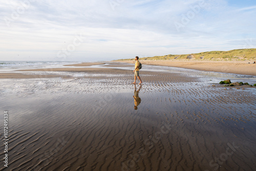 Man figure on the North sea beach with the sandy dunes in the background not far from Den Helder town in the province of North Holland, the Netherlands