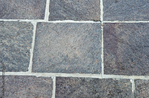 The sidewalk is paved with stone tiles