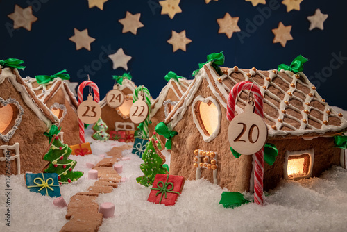 Christmas gingerbread village with stars at night on snowy scene.