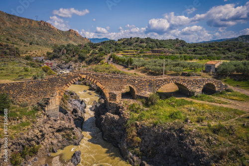 Ponte dei Saraceni. An ancient medieval bridge of Norman age located on the Simeto river. Adrano - Catania, in Sicily. Aerial drone picture. June 2023