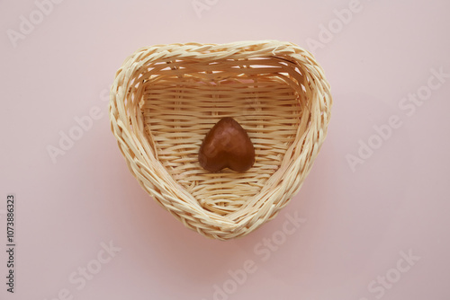 A heart-shaped candy lying upside down in a heart-shaped basket, insincere feelings, contradictory emotions, inauthenticity of feelings, incompatibility of a loving couple, loneliness during holidays