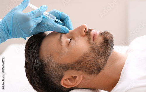 Side view of middle-aged man getting beauty injection in nose at aesthetic clinic. Plastic surgeon injecting anti-aging filler in handsome bearded man nose, having plastic correction, closeup