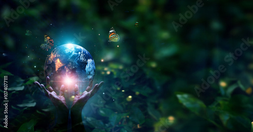 Hands protecting blue earth on tropical green forest nature background, Earth day, Ecology and Environment concept.