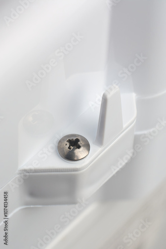 close-up of phillips crosshead screw head mounted on white textured plastic product or appliance surface, soft focus with copy space