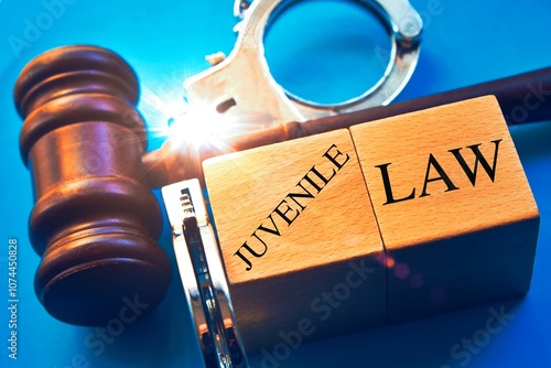 "Juvenile law" word with gavel and handcuffs on a blue background.