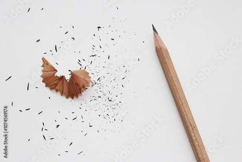 Graphite pencil, sharpener and shavings on white background, flat lay. 