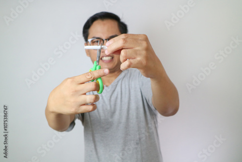 one cigarette through the blades of a scissors for kids. white and blue color scissors for child's activities. stop smoking concept. take down national day of action. world no tobacco day. free space