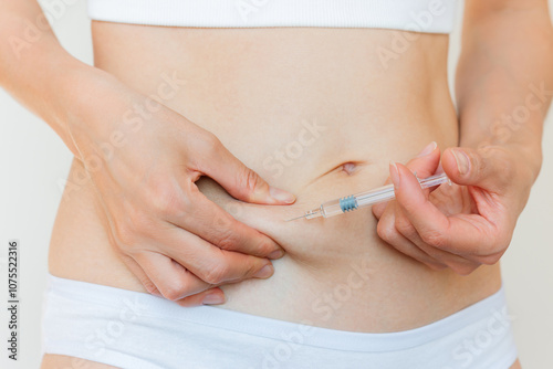 A young Caucasian woman in white underwear giving herself a subcutaneous injection into her stomach. Women's reproductive health. Trigger ovulation