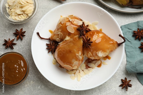 Delicious pears with caramel sauce, almond flakes and anise stars on grey table, top view