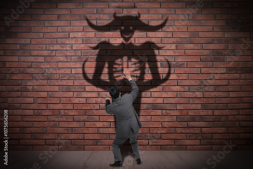 Businessman scared by monster. Scary shadow on brick wall