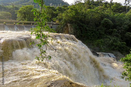 A scenic view of the Ribeirão da Antas Hydroelectric Plant, surrounded by lush greenery and water flow. The structure blends with the natural landscape, highlighting renewable energy in Brazil.