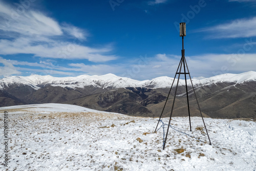 The triangulation point on Mariam summit and Pambak Range cowered with snow on sunny spring day. Aghavnadzor, Armenia.