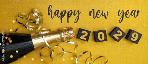 happy new year, silvester, new year's eve party celebration greeting card with text - Champagne bottle, ribbons and cubes with year number 2029, on golden glitter table background, top view, flat lay