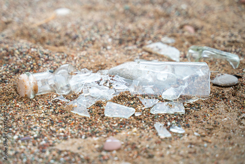 Shattered glass bottle scattered on a sandy beach, capturing the environmental impact of littering and pollution on natural landscapes.