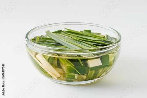 A beneficial extract or infusion of lili chai lemongrass or green tea for weight loss and health displayed in a glass bowl on a white background