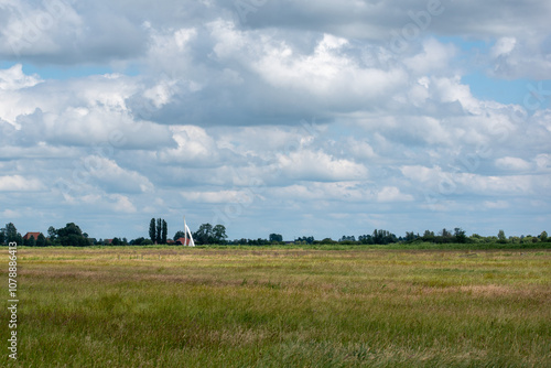 Typical Dutch polder landscape with clouds and sailboat at nature reserve Bloksloot (Bloksleat), Friesland, the Netherlands