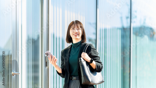 屋外でスマホを持つ若い女性・ビジネスウーマン