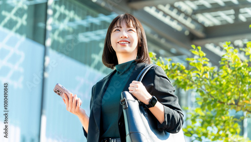 屋外でスマホを持つ若い女性・ビジネスウーマン