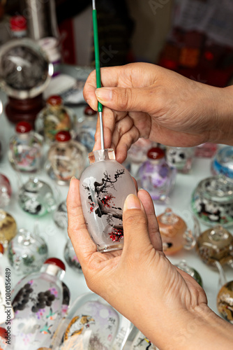 Manos de mujer pintando un frasco de cristal.