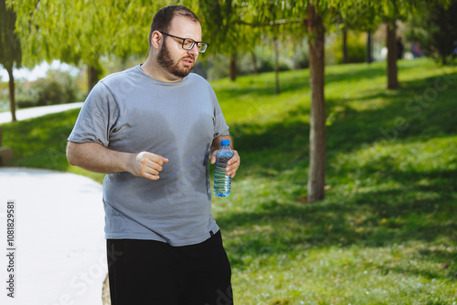 Man with excess weight jogging in the park and feel unhealthy, heart problems.