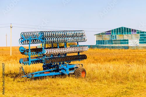 a trailed harrow stands in a field. harrowing the soil. harrow trailer for tractor