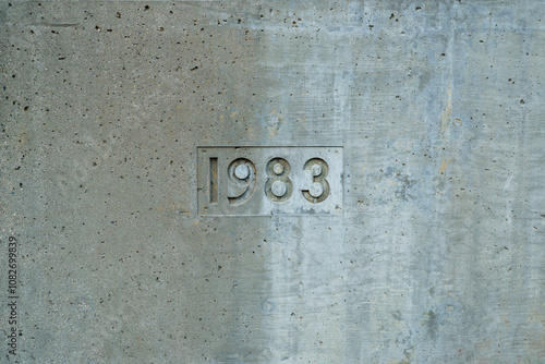 The year 1983 is carved into a concrete wall