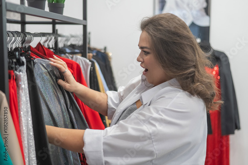 Happy plump woman chooses clothes in a store. Plus size clothing. 