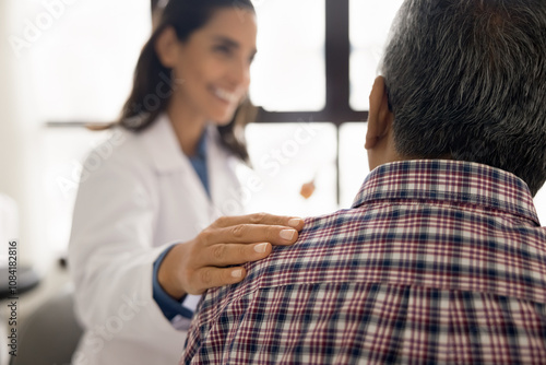 Close up kind female therapist touch shoulder of senior male patient during conversation at his visit in clinic, discuss successful therapy, effective treatment, encouraging, giving support. Eldercare