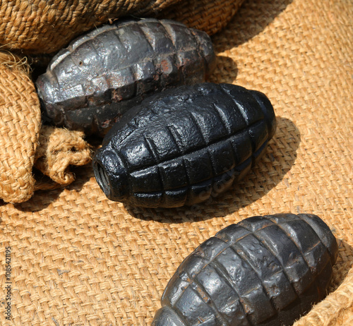 three black grenades or hand grenades on a jute background used during the war