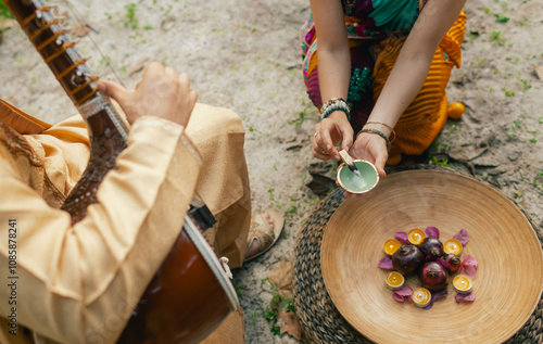 Indian musician in traditional clothes playing sitar festive season outdoor home. Woman in traditional saree hand lighting Diya lamp during Diwali festival. Happy greeting photo. Part of a series